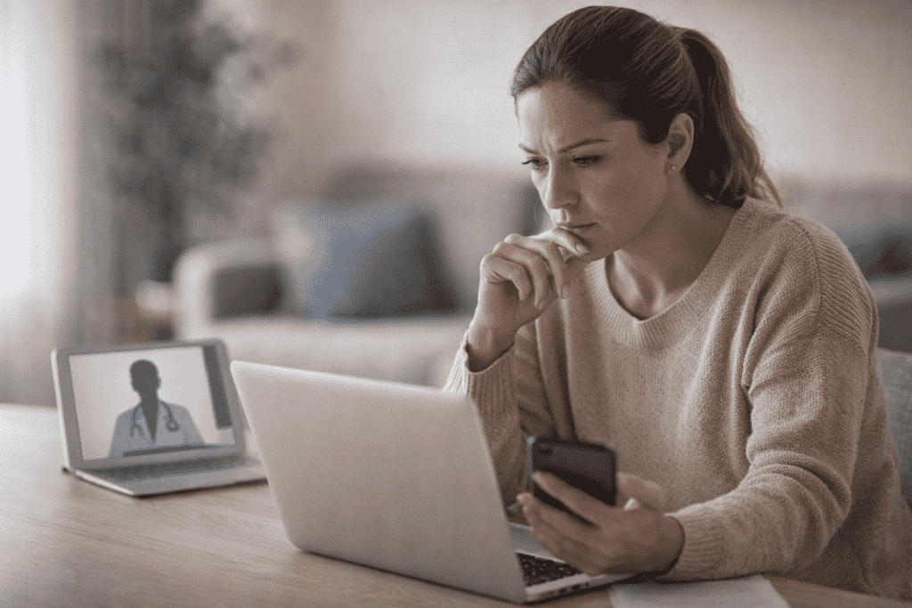 Adult reviewing health information on a laptop at home while considering urgent care options in Toronto.